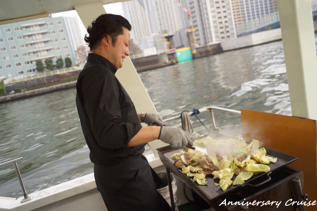 船の上で肉と野菜を焼く男性の写真