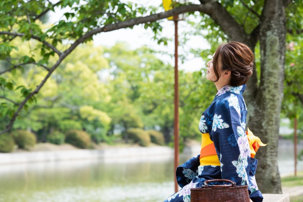 川辺で一休みする浴衣の女性