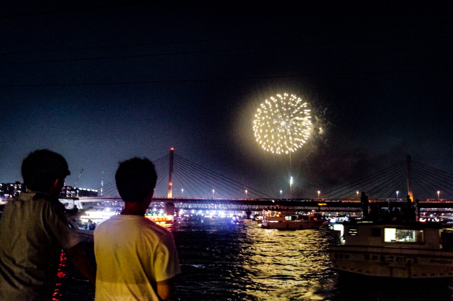 江東花火大会において船上から打ち上げ花火を眺める人たち